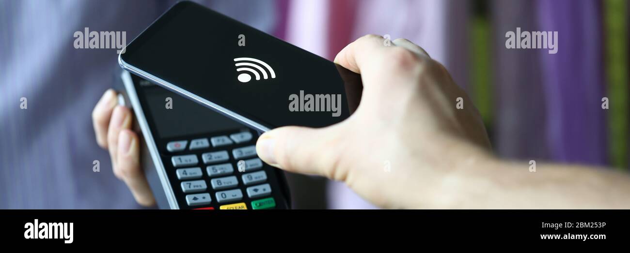 La mano tiene fuori il terminale per il pagamento con carta di credito Foto Stock