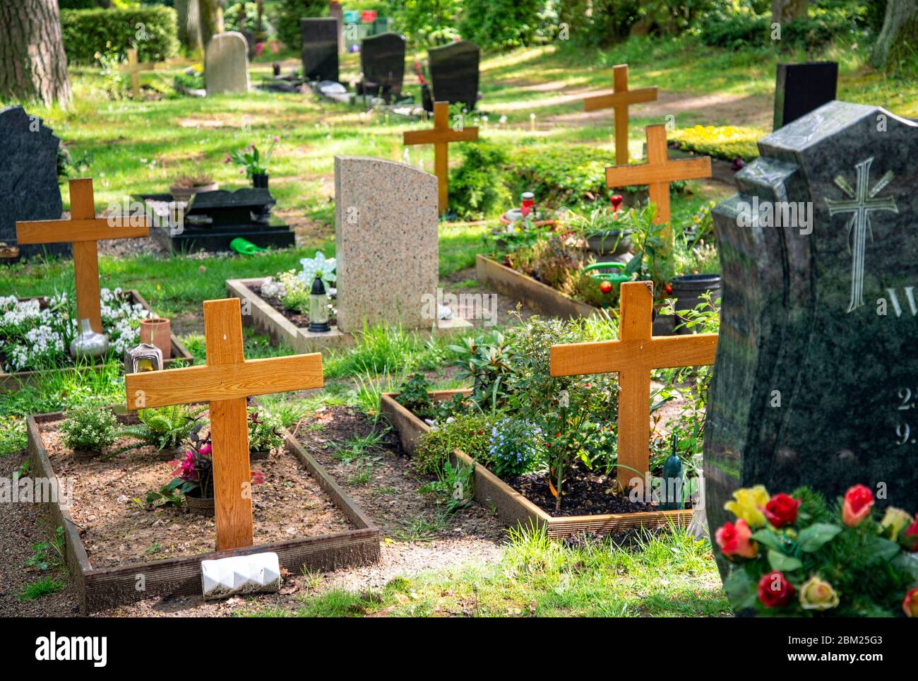 Tombe con lapidi e croci in legno in un cimitero Foto Stock