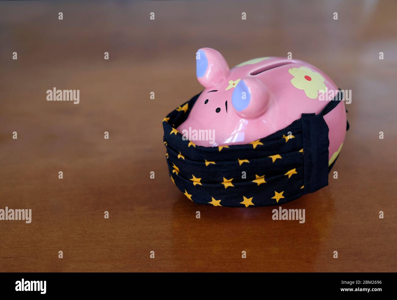 Blocco e l'impatto finanziario: Piggy banca indossare una maschera facciale Foto Stock