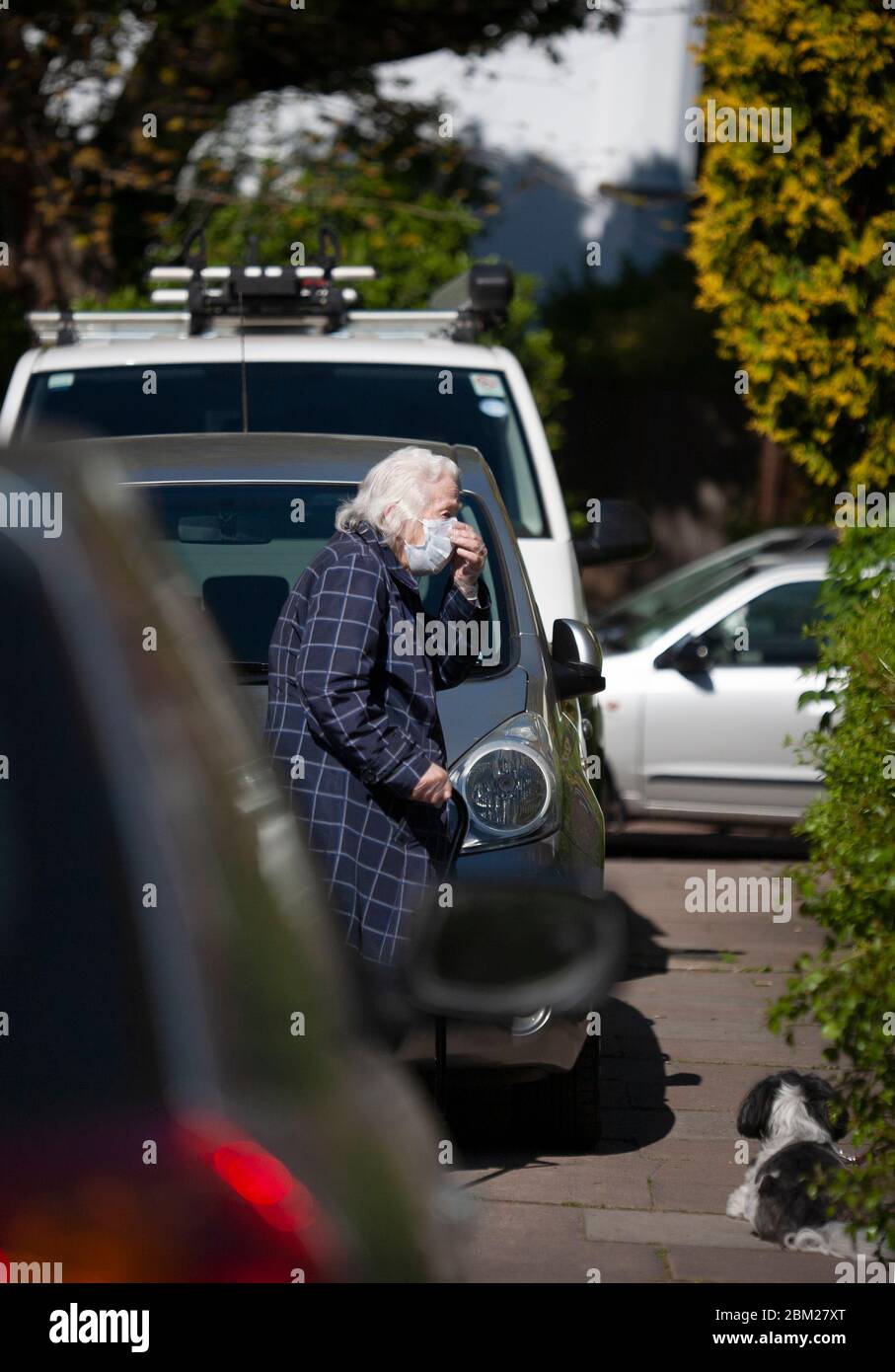 Donna anziana indossava i dispositivi di protezione individuale e toccarla maschera durante la pandemia 2020 COVID-19. Balham, Londra Regno Unito Foto Stock