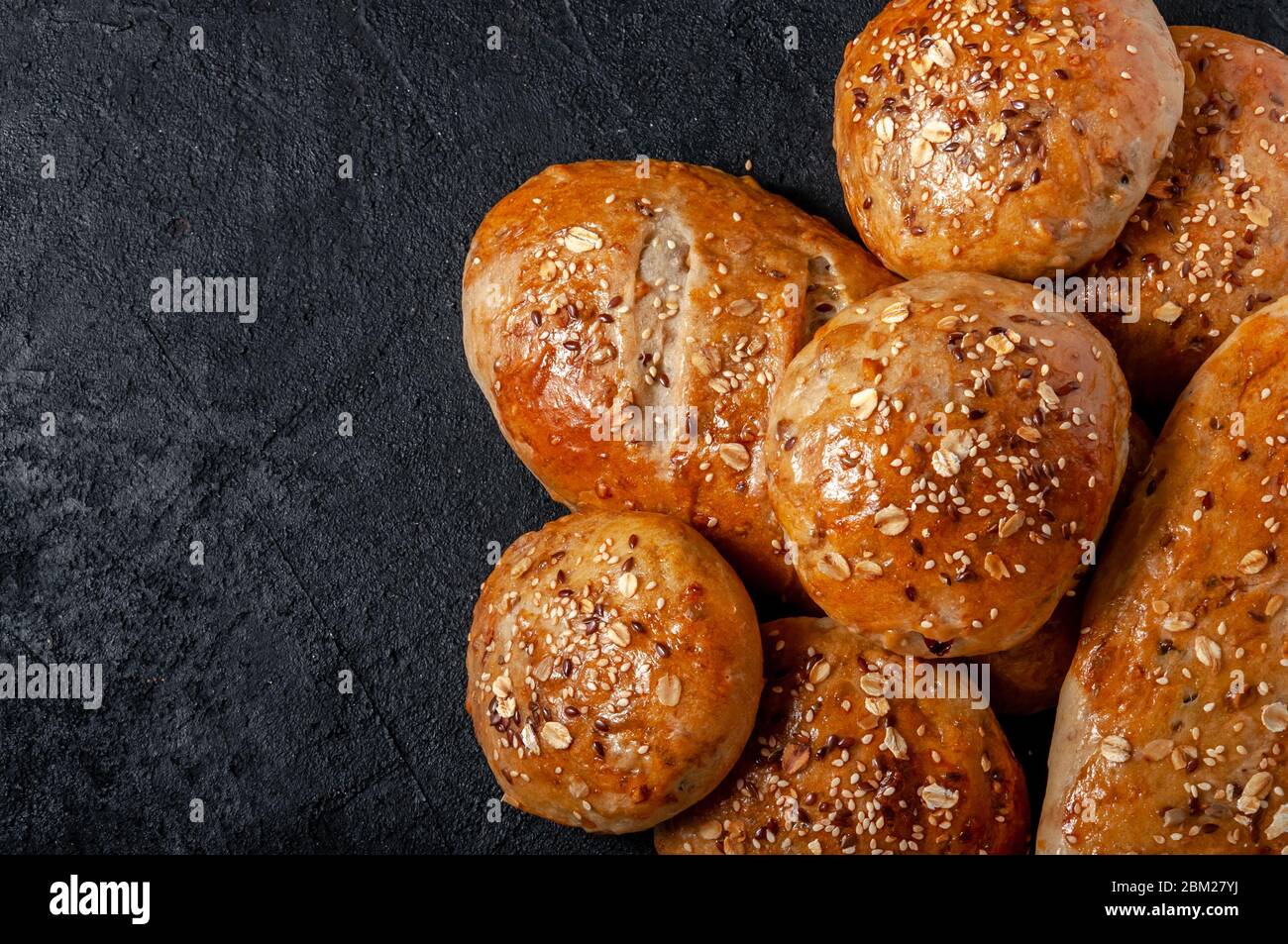 Pane integrale e panini fatti in casa con semi di lino e sesamo su Dark Table. Visualizzazione dall'alto piatto. Spazio copia Foto Stock