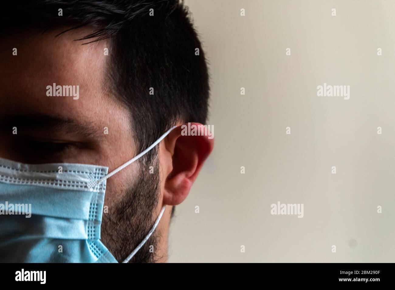 Ritratto di un maschio con maschera blu in uno spazio interno. Ritratto psicologico degli effetti della quarantena per la crisi di Coronavirus Foto Stock