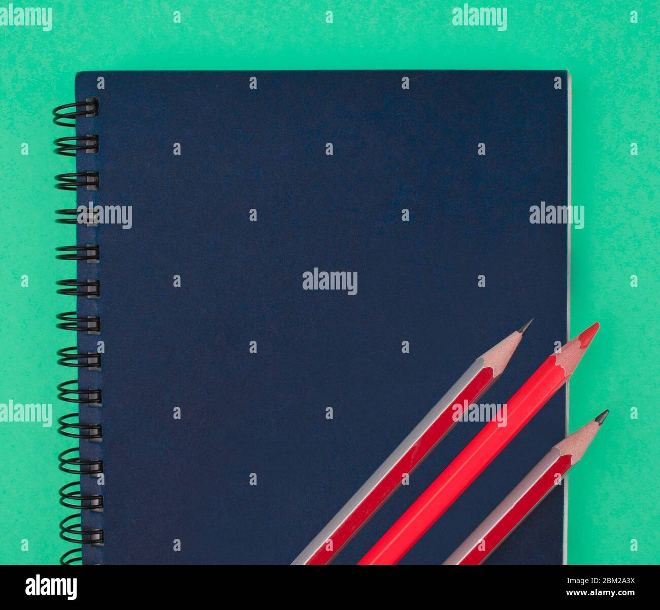 Tre pastelli di legno rosso matita posti sopra un diario di carta blu Foto Stock