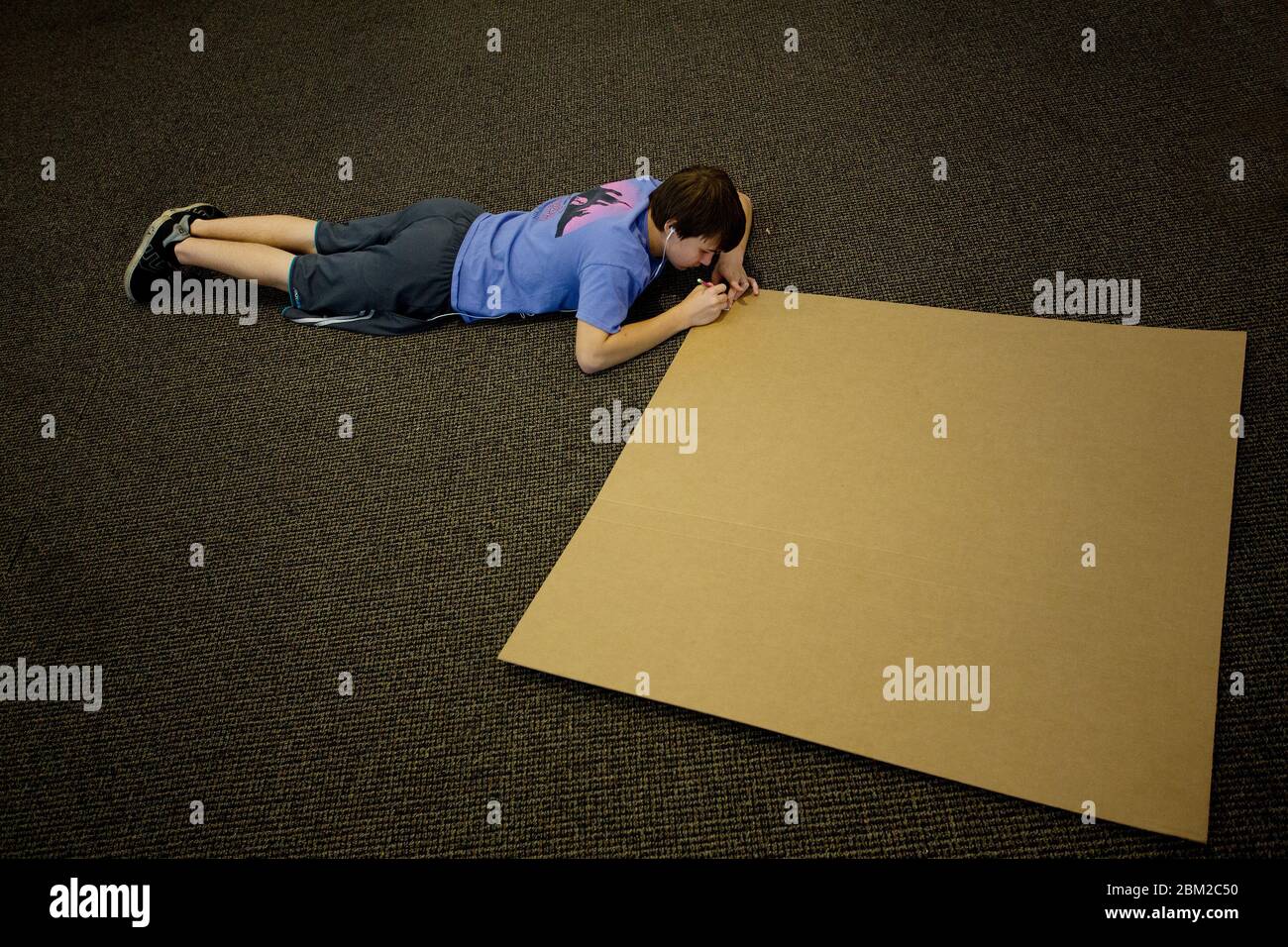 Il ragazzo adolescente comincia a disegnare su grande bordo del manifesto Foto Stock