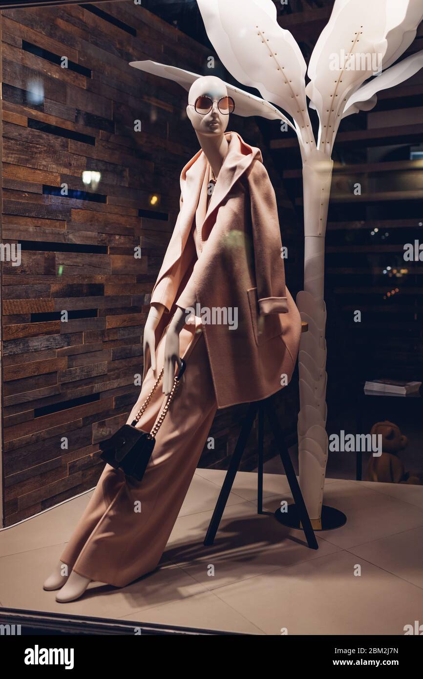 Manichino vestito con abiti femminili primaverili in mostra di un negozio nel centro della città di notte. Concetto di shopping e vendite Foto Stock