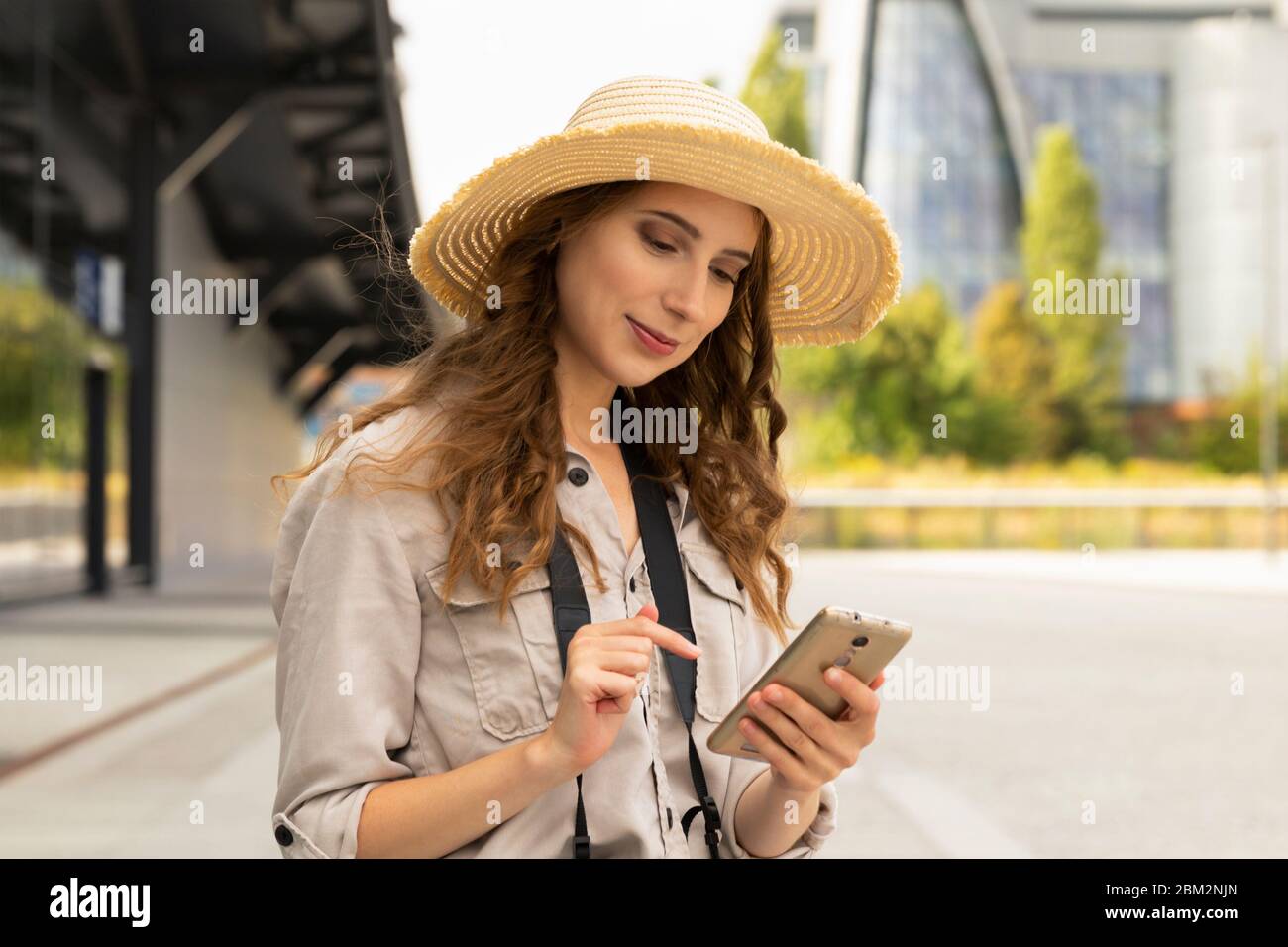 Immagine di giovane eccitato bella donna in posa turistica. Una donna con una valigia si trova alla stazione, comunica con qualcuno al telefono. Foto Stock