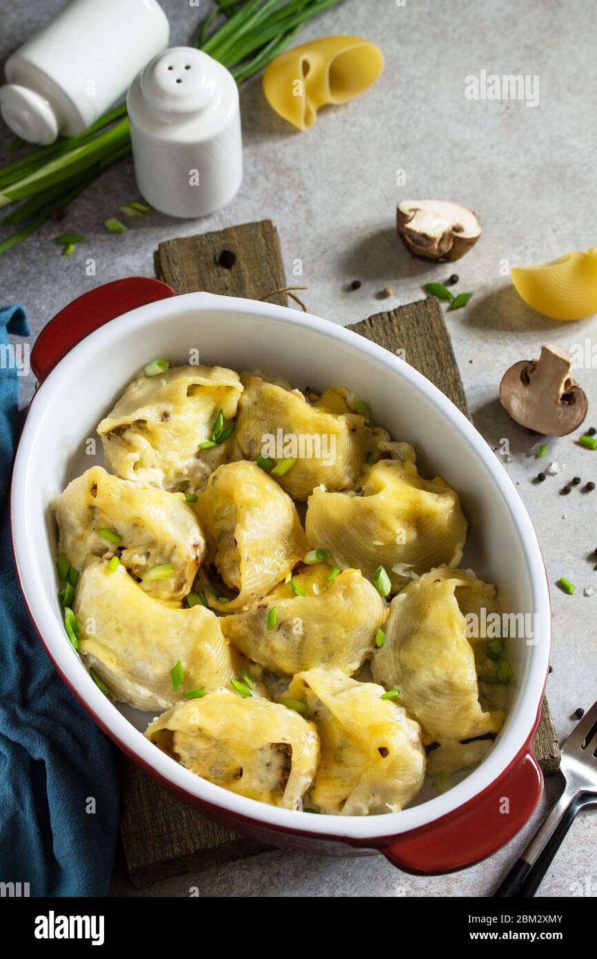 Pasta italiana Conchiglioni rigati ripieni di pollo, champagne reali, cotti con formaggio in salsa di bechamel su un piano in pietra grigia. Spazio di copia. Foto Stock