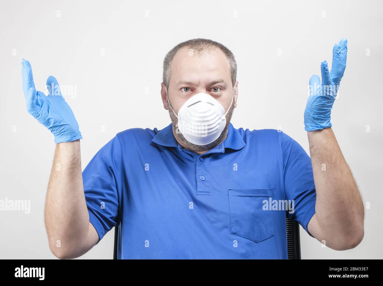 Ritratto di uomo caucasico confuso che indossa guanti e maschera medici protettivi. Le persone si sono irritate indossando un equipaggiamento di protezione per rallentare la diffusione Foto Stock