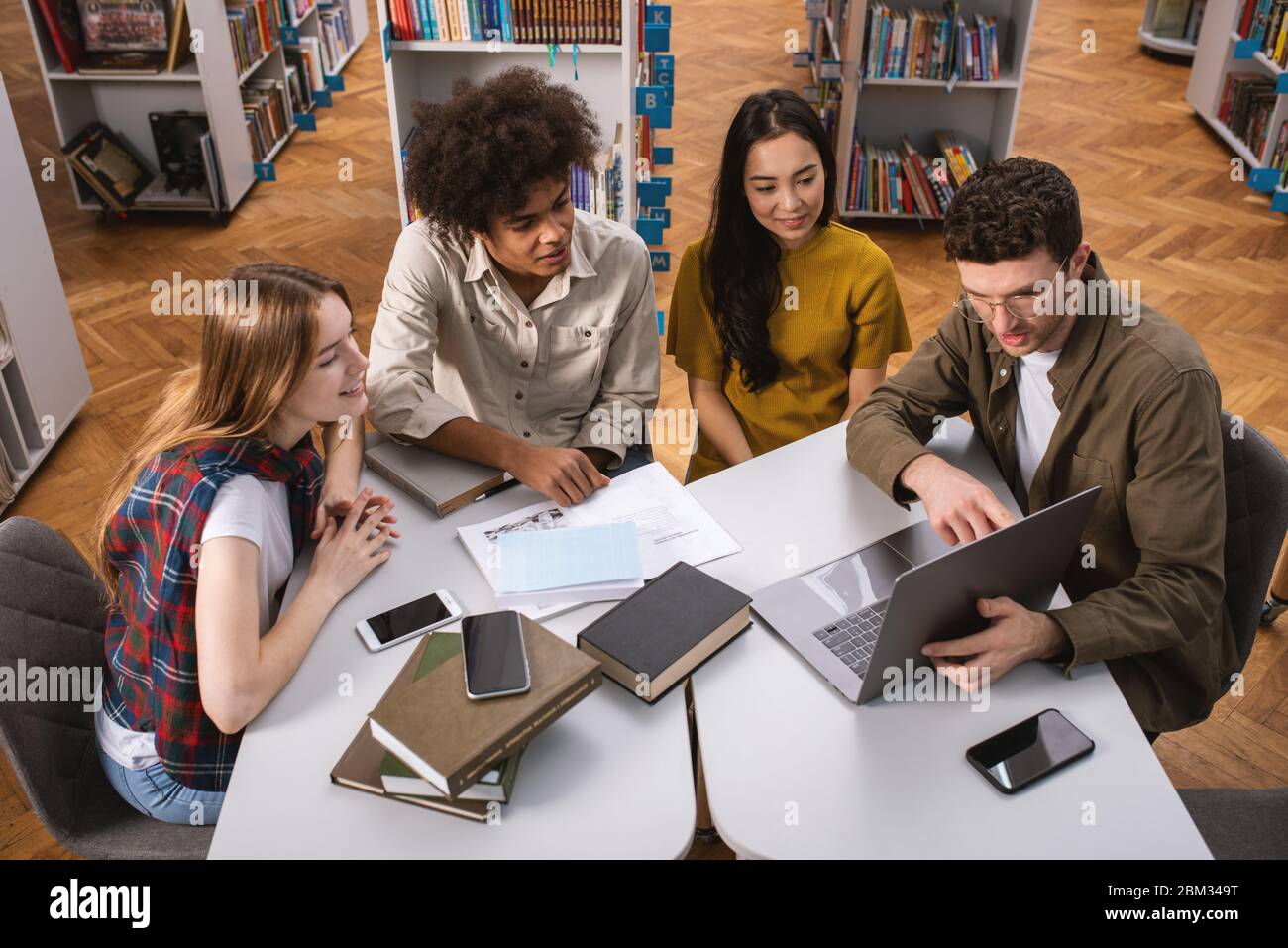 Gli studenti universitari stanno studiando in una libreria insieme. Concetto di lavoro di squadra e la preparazione Foto Stock