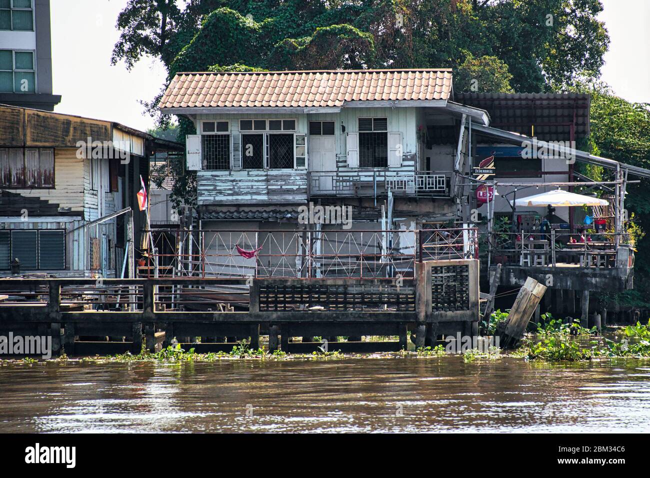 Bangkok, Thailandia 01.04.2020: Case thailandesi con architettura tradizionale, segni, simboli sulla riva del fiume Chao Phraya Foto Stock