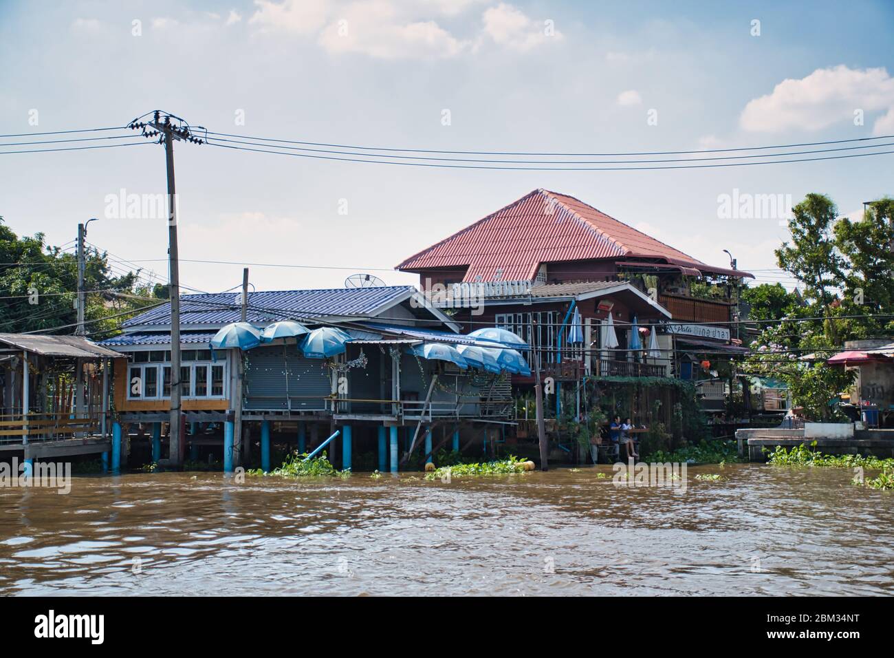 Bangkok, Thailandia 01.04.2020: Case thailandesi con architettura tradizionale, segni, simboli sulla riva del fiume Chao Phraya Foto Stock
