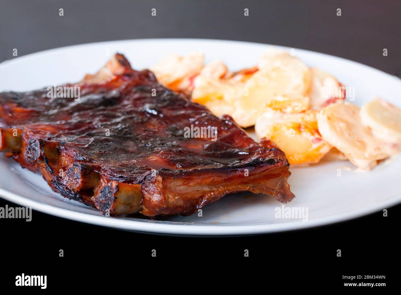 Costolette di ricambio grigliate piccanti, servite su un piatto con patate scagliate alla paprika. Immagine ravvicinata Foto Stock
