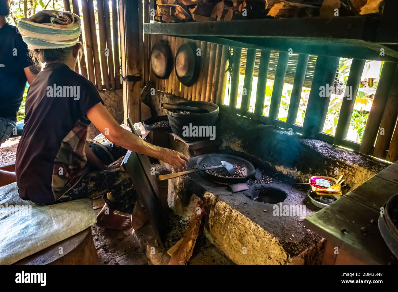 Vecchia donna balinese torrefazione caffè chicchi con metodo tradizionale Foto Stock