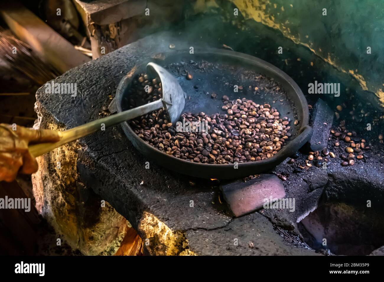 Vecchia donna balinese torrefazione caffè chicchi con metodo tradizionale Foto Stock