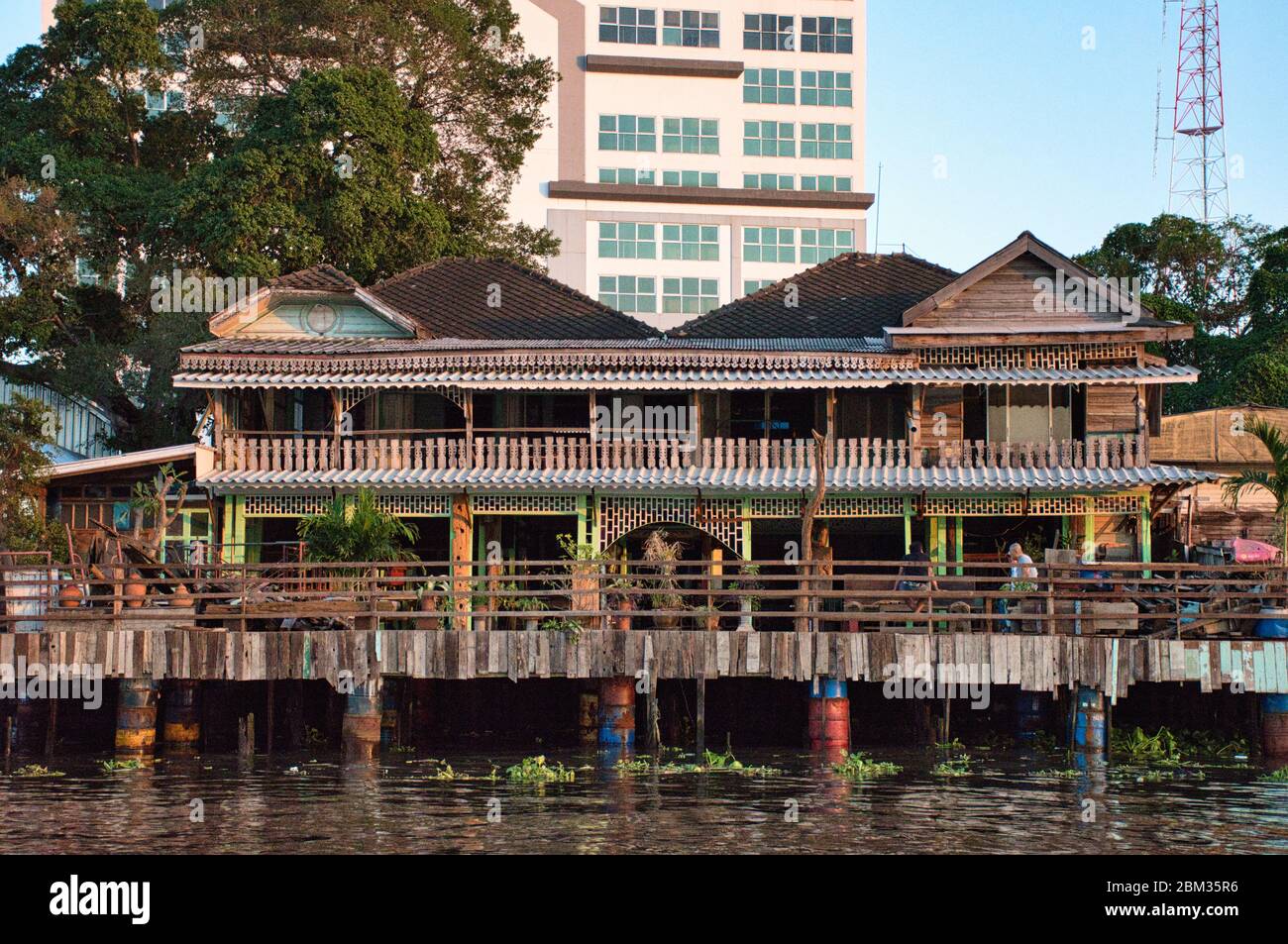 Bangkok, Thailandia 01.04.2020: Case thailandesi con architettura tradizionale, segni, simboli sulla riva del fiume Chao Phraya Foto Stock