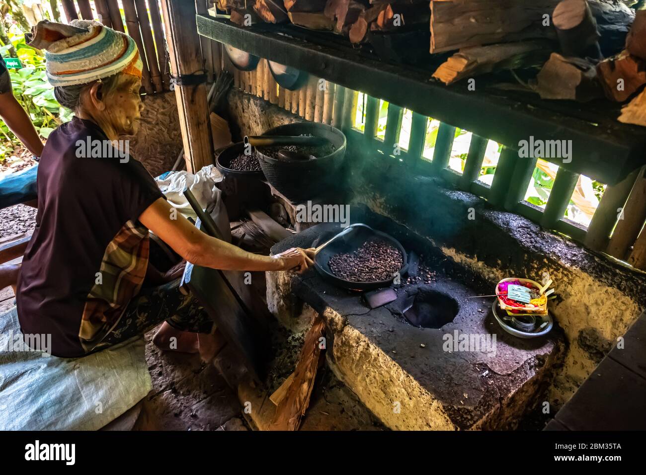 Vecchia donna balinese torrefazione caffè chicchi con metodo tradizionale Foto Stock