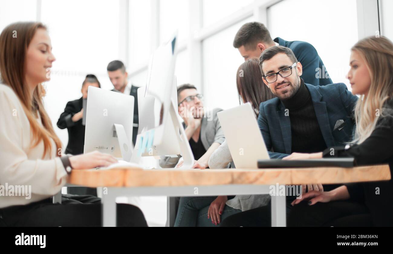 Giovane imprenditore e gruppo di lavoro seduto al banco dell'ufficio Foto Stock