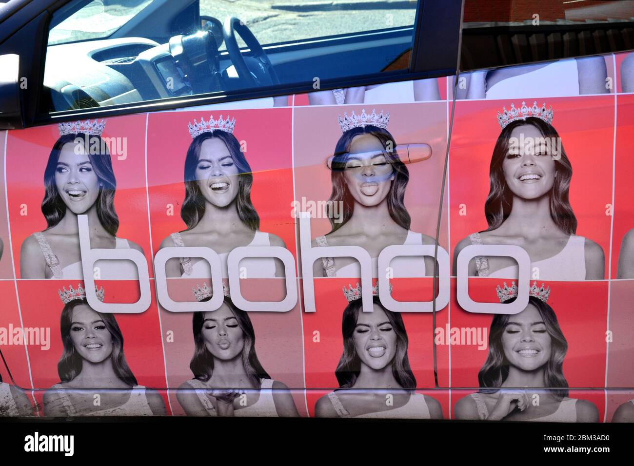 Pubblicità per la gamma di abbigliamento femminile di Boohoo e le ultime tendenze della moda con una donna sul lato di un'auto Manchester, Inghilterra, regno unito Foto Stock