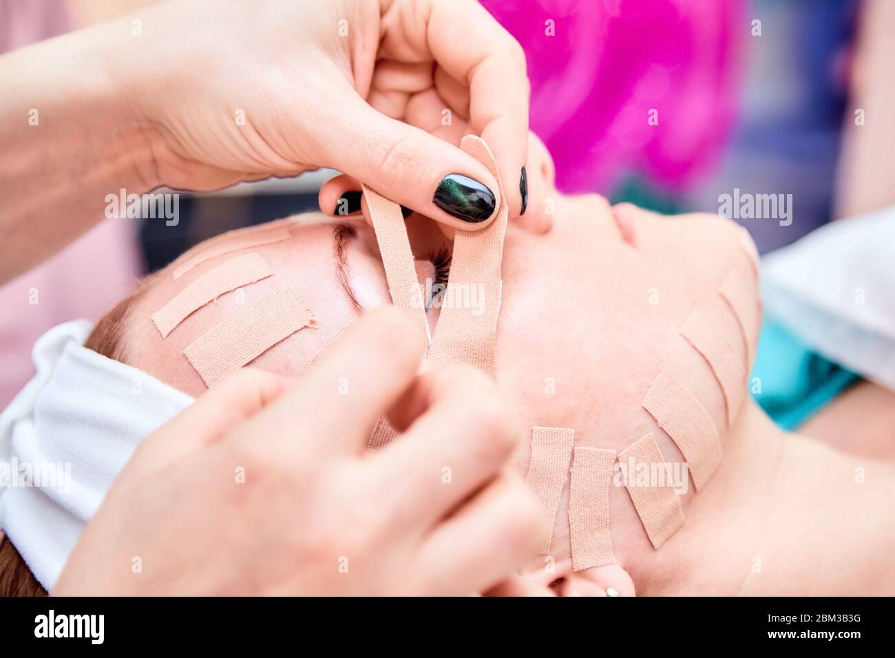 Kinesiotaping. Nastro adesivo estetista sul viso di una donna. Procedura fisioterapica e cosmetologica. Metodo di ringiovanimento cutaneo non chirurgico. FAC Foto Stock