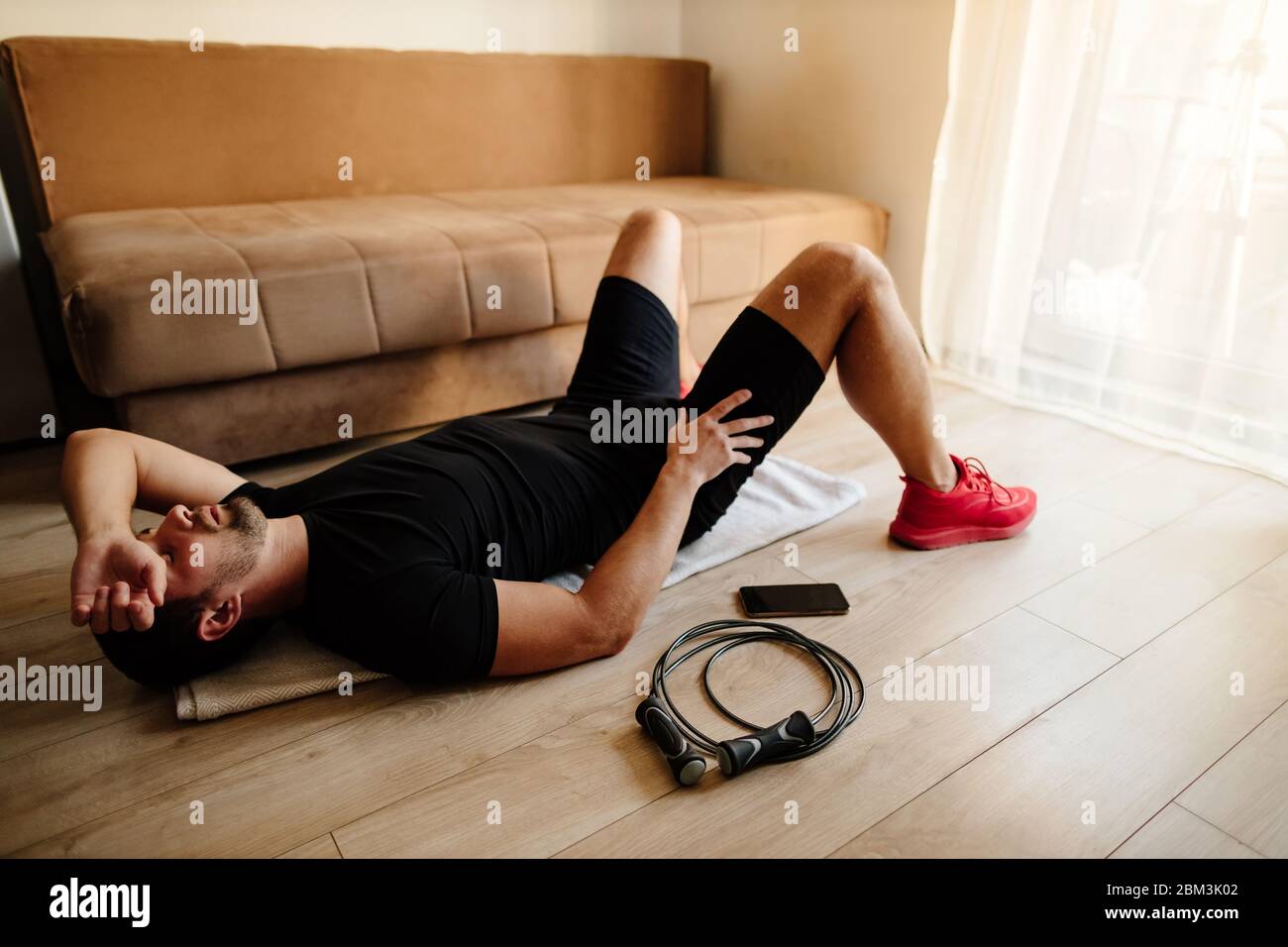 uomo adulto rilassarsi dopo la ginnastica. uomo stanco dopo la ginnastica di fitness poggiato sul pavimento. Foto Stock