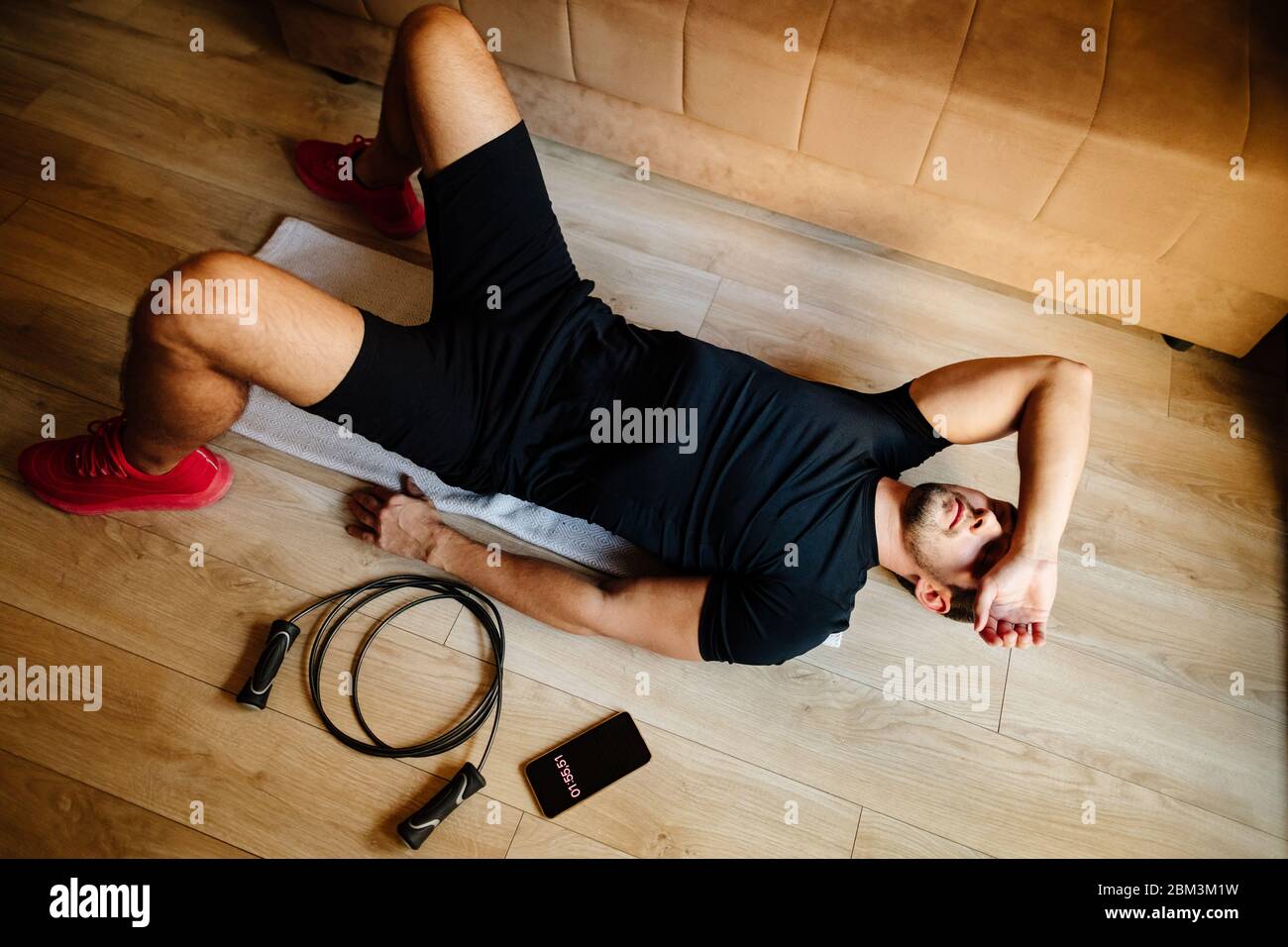 uomo adulto si rilassa dopo la allenazione. uomo stanco dopo l'allenamento sul pavimento. sindrome da overtraining stanchezza Foto Stock