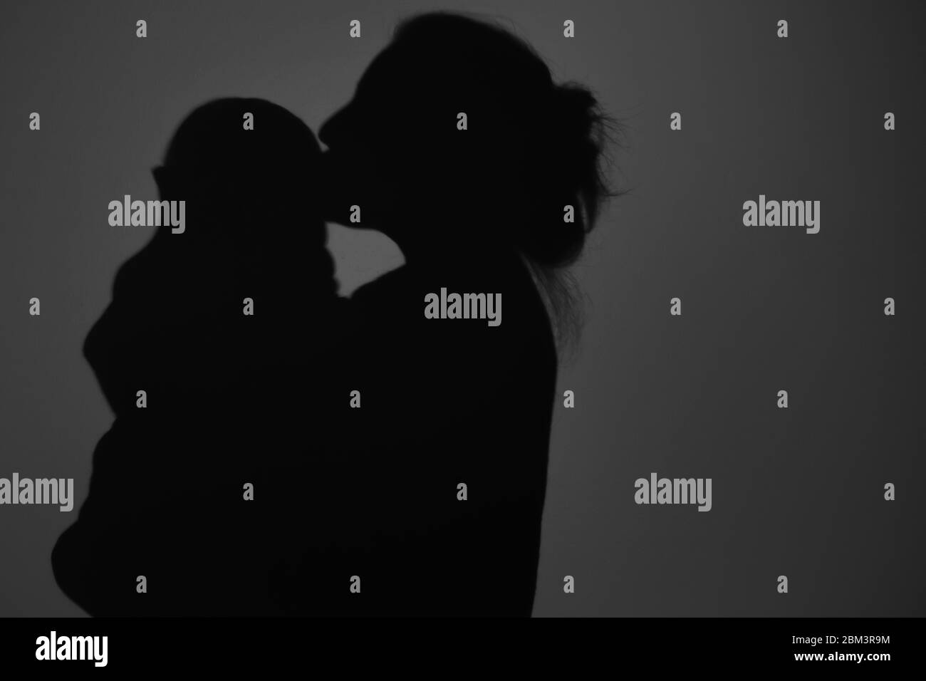 Silhouette di Madre e Bambino felice. Mamma bacia il bambino, felice concetto di Festa della mamma Foto Stock