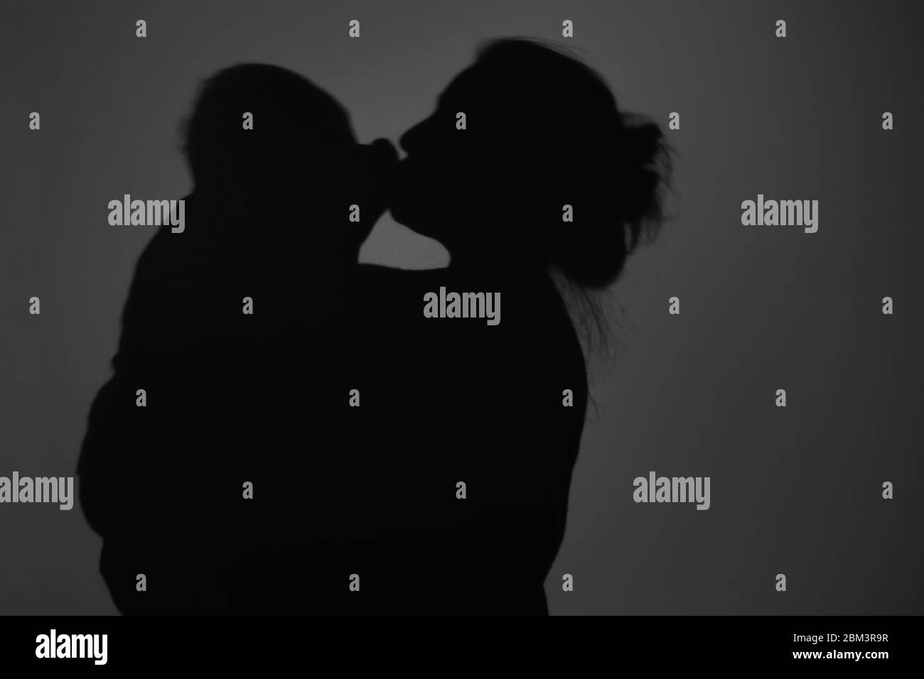 Silhouette di Madre e Bambino felice. Mamma bacia il bambino, felice concetto di Festa della mamma Foto Stock