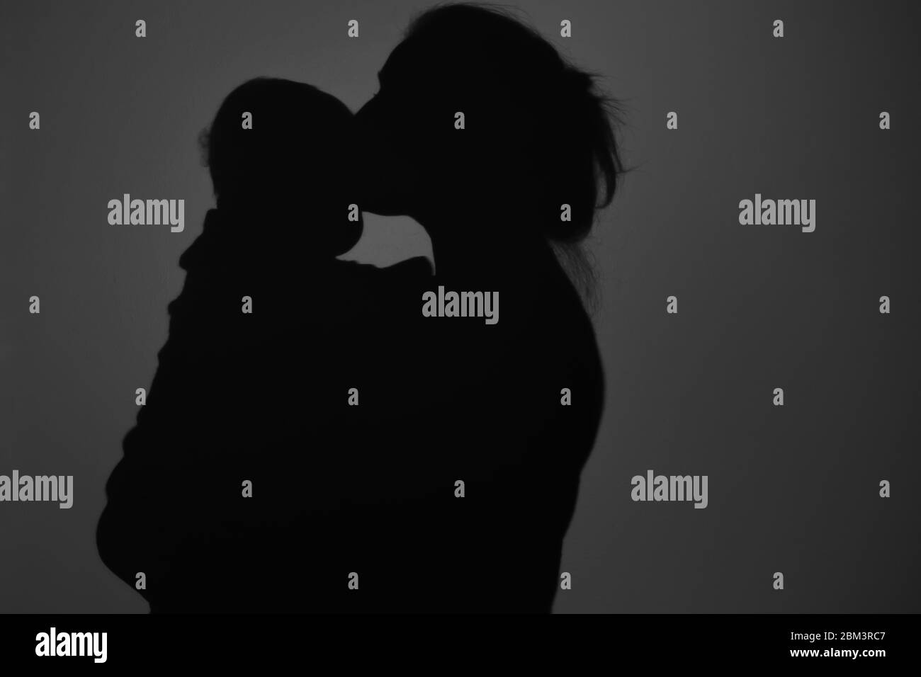 Silhouette di Madre e Bambino felice. Mamma bacia il bambino, felice concetto di Festa della mamma Foto Stock