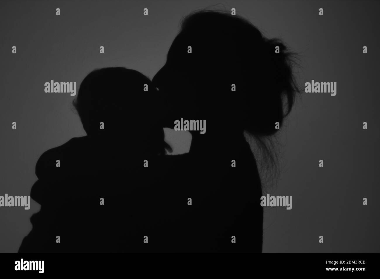 Silhouette di Madre e Bambino felice. Mamma bacia il bambino, felice concetto di Festa della mamma Foto Stock