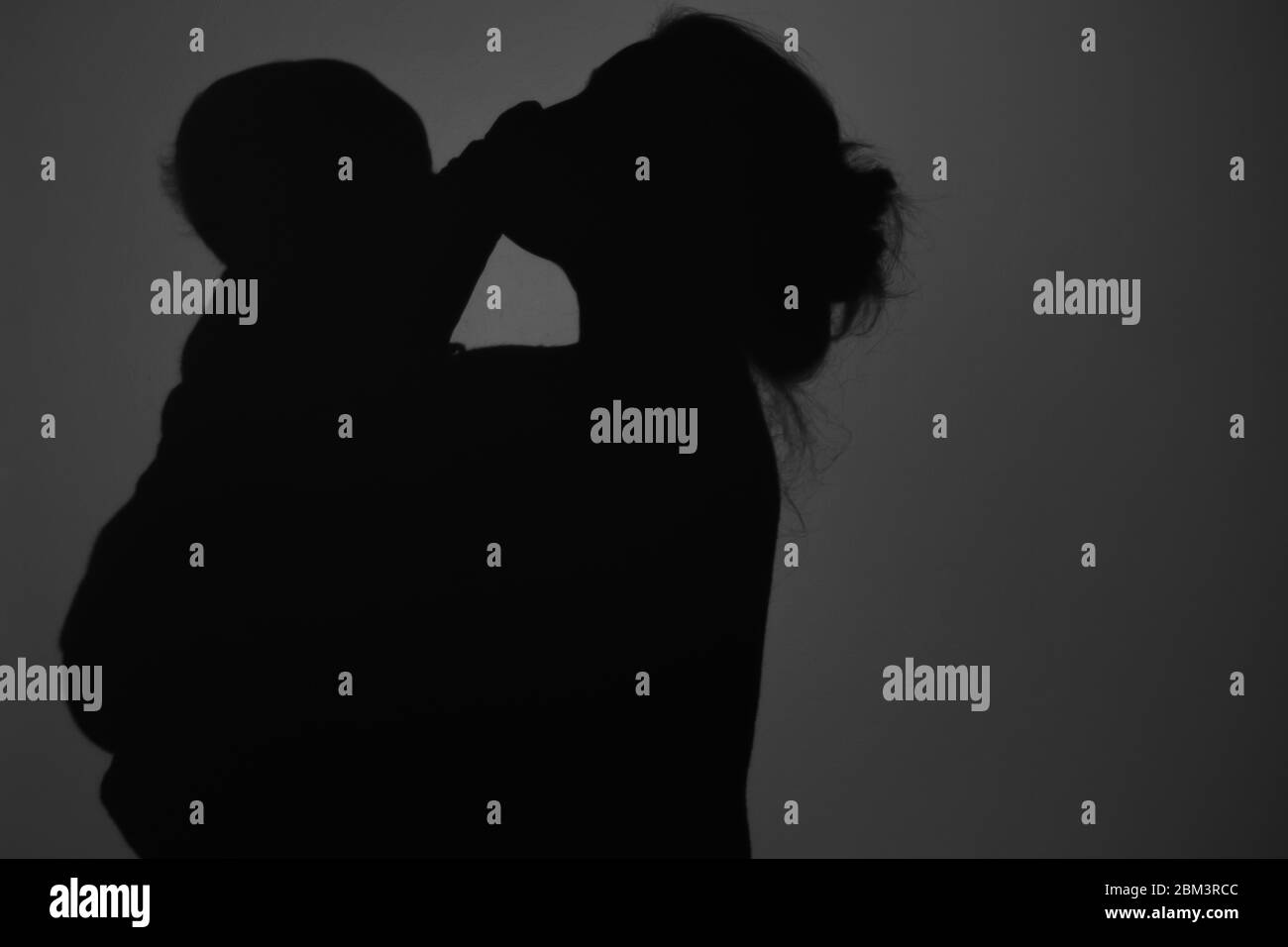 Silhouette di Madre e Bambino felice. Mamma bacia il bambino, felice concetto di Festa della mamma Foto Stock