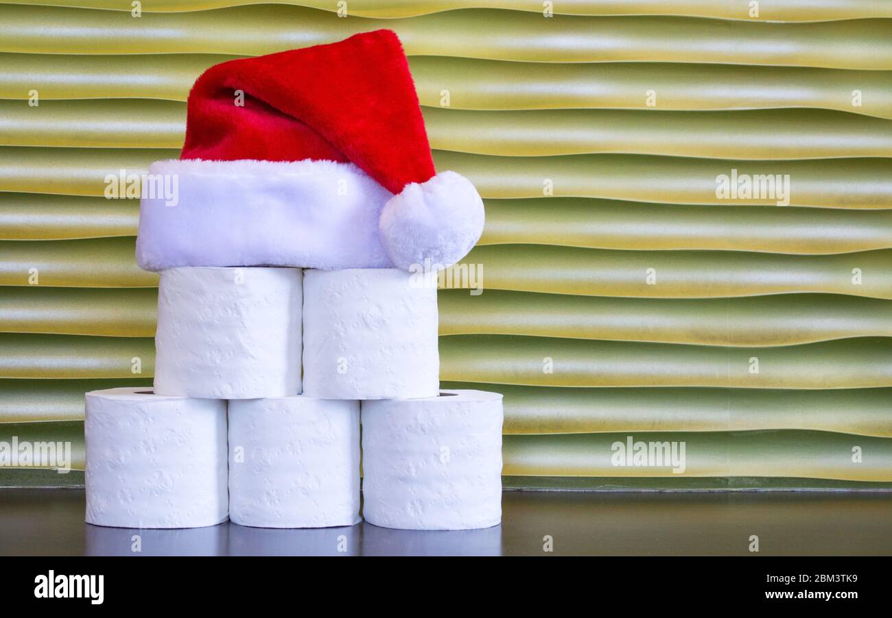 Rotoli di carta igienica impilati a forma di piramide con un cappello Babbo  Natale rosso e bianco sulla parte superiore, su uno sfondo dorato con  spazio per le copie Foto stock -