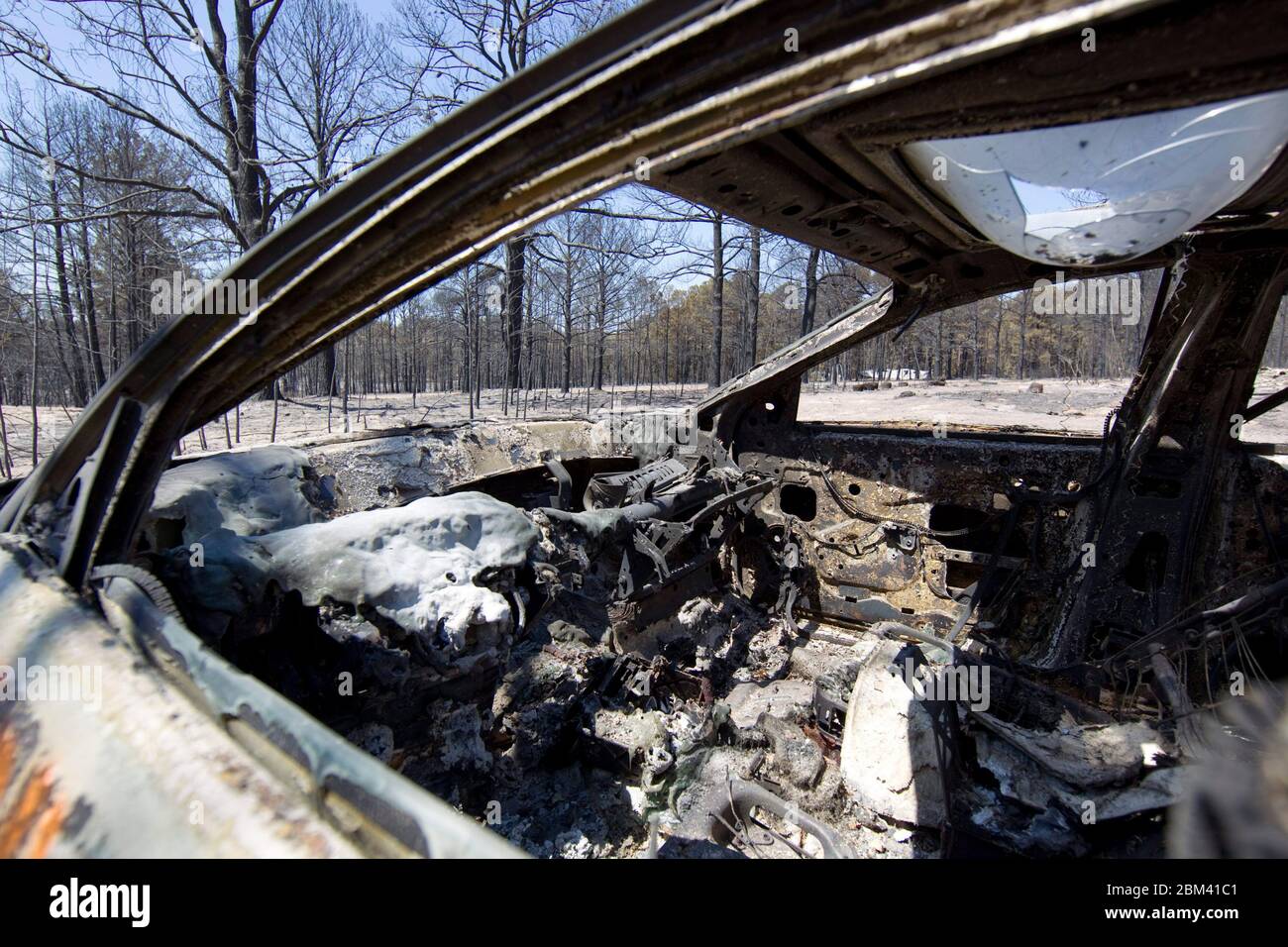 Bastrop County Texas USA, 9 2011 settembre: Un'auto bruciata si trova di fronte a una casa livellata in una zona pesantemente boschiva colpita da incendi boschivi. Gli incendi distrussero 1.500 case e bruciarono oltre 40.000 ettari di terreno, mentre era fuori controllo per cinque giorni. ©Bob Daemmrich Foto Stock