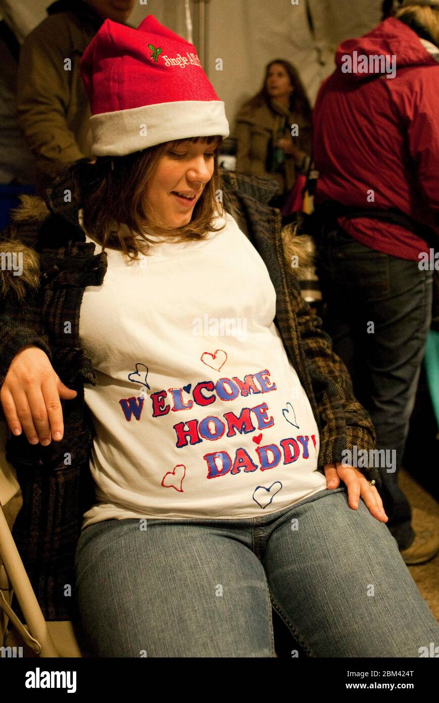 Fort Hood Texas USA, 24 dicembre 2011: Una donna incinta fa sport un cartello di benvenuto sul suo baby Bump mentre aspetta che il marito arrivi a casa dal suo schieramento dell'esercito in Iraq. ©Marjorie Kamys Cotera/Daemmrich Photography Foto Stock