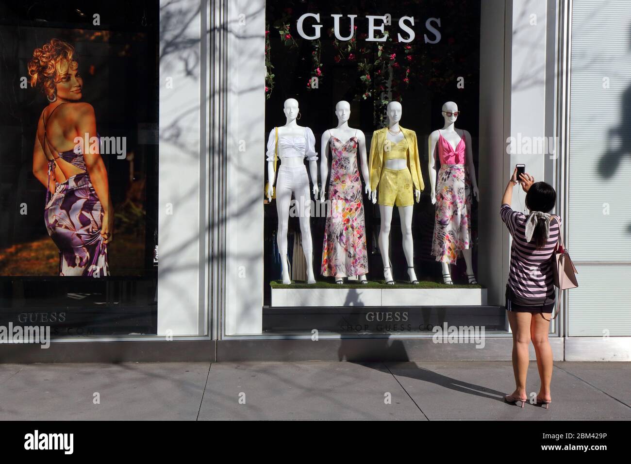 Una persona prende una foto della moda primaverile mentre fa shopping alla finestra a GUESS, 575 Fifth Ave, New York Foto Stock