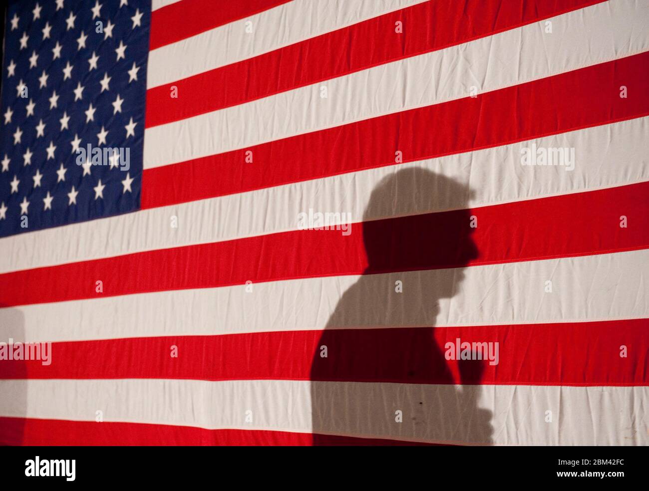Boone, Iowa USA, 31 dicembre 2011: Rick Perry, candidato alla nomina presidenziale repubblicana, fa una spinta finale con gli elettori di Iowa caucus durante un incontro e un saluto alla Dutch Oven Bakery, dove la sua ombra è gettata su una grande bandiera americana. Il governatore del Texas sta lottando per rilanciare la sua campagna dopo aver costantemente calato nella maggior parte dei sondaggi da quando diverse persone affarate hanno fatto deragliare i suoi sforzi per rimanere un top contender nelle primarie repubblicane. ©Bob Daemmrich Foto Stock