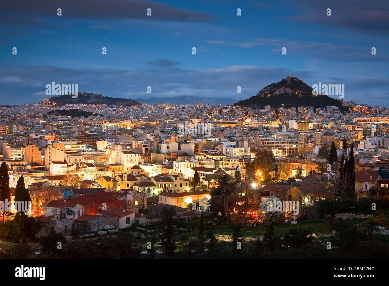 Vista della notte Atene e Likabetus collina dalla collina Areios Pagos dove le prove si svolgevano in tempi antichi. Foto Stock