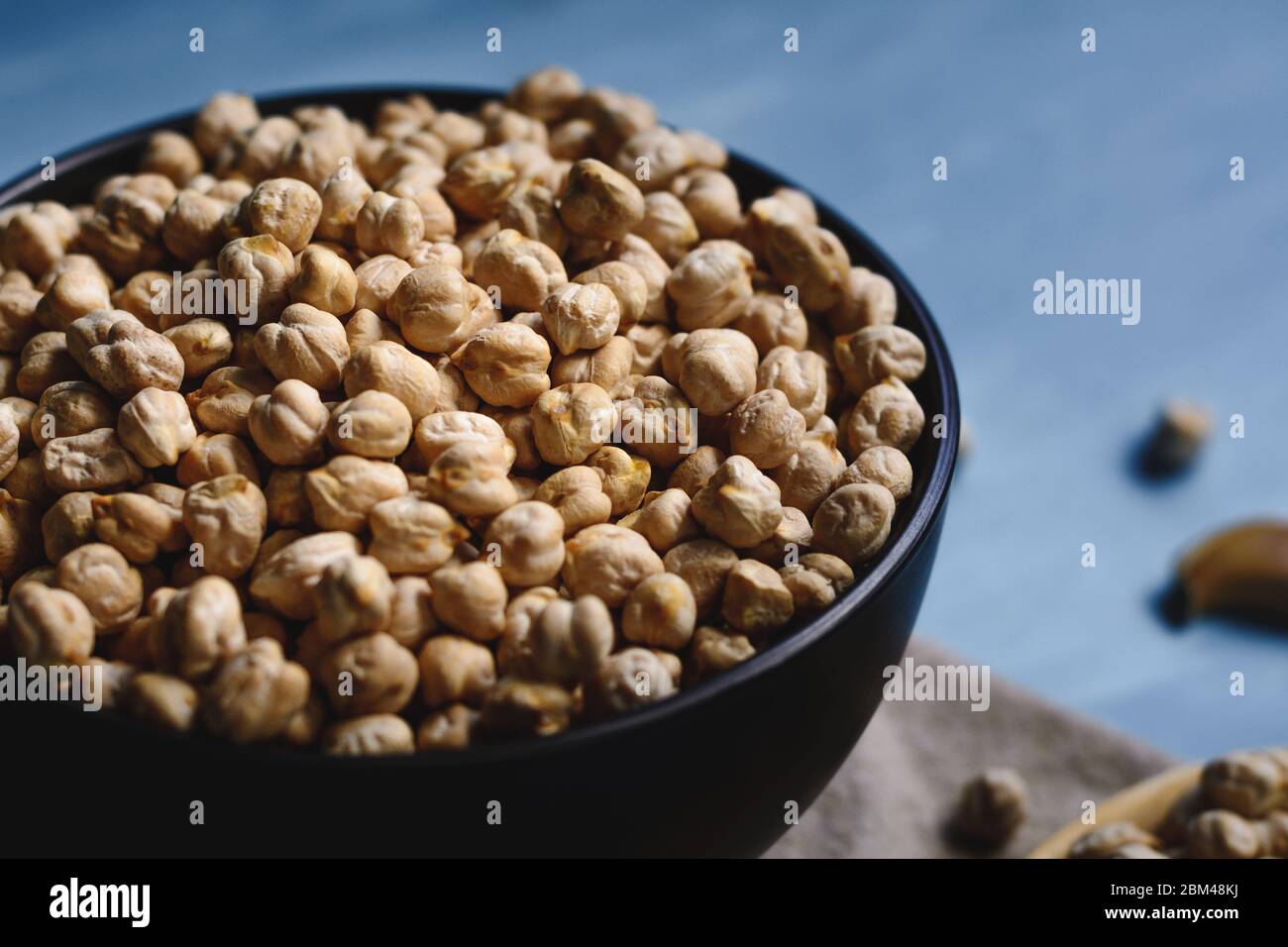 Ceci crudi in una ciotola e cucchiaio di legno. Foto Stock