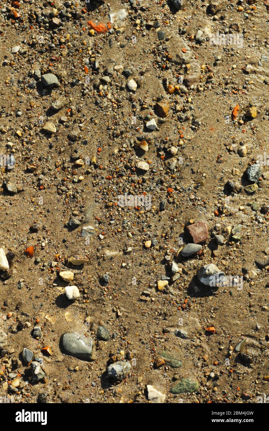Piccole pietre e sabbia. La struttura naturale del suolo. Riva di un bacino idrico con una spiaggia e ciottoli. Foto Stock