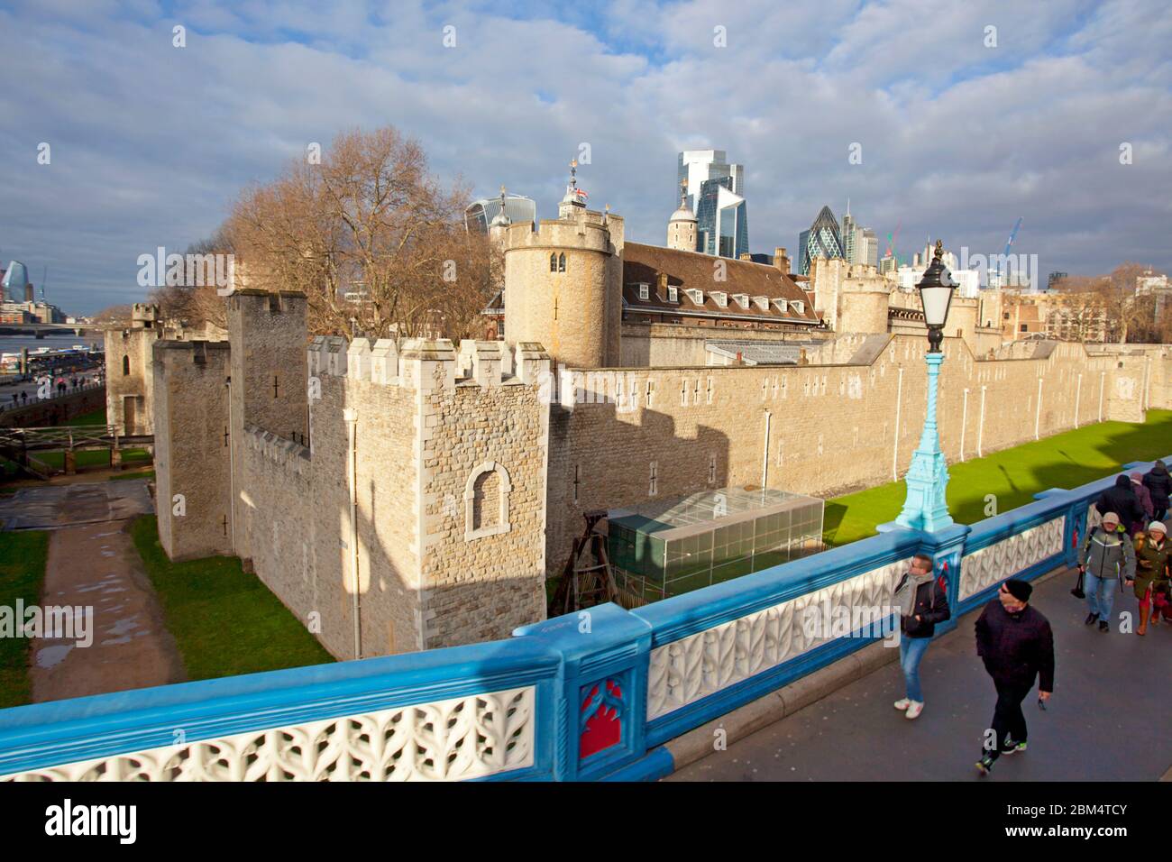 Persone che camminano lungo il Tower Bridge con la Torre di Londra sullo sfondo Foto Stock