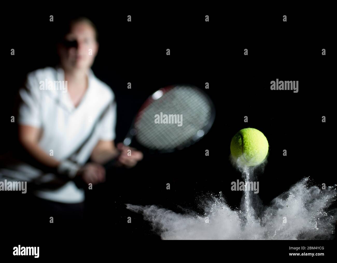 Una palla da tennis che rimbalza sulla linea con la polvere di gesso e un giocatore fuori fuoco sullo sfondo con una racchetta. Concettuale, con sfondo nero Foto Stock