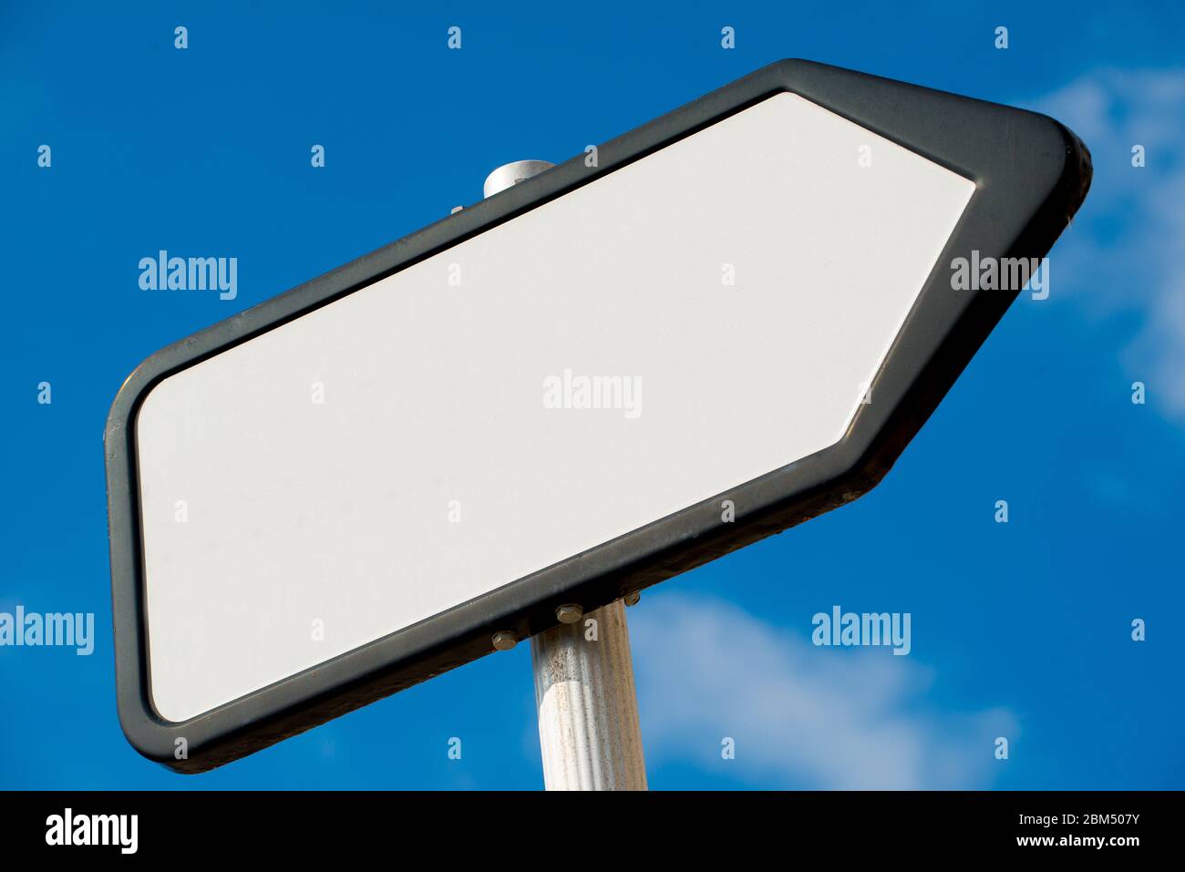 Vista ad angolo basso di un bianco, bianco, che punta il senso, posto di segnale di informazioni contro un cielo blu con le nuvole. Foto Stock