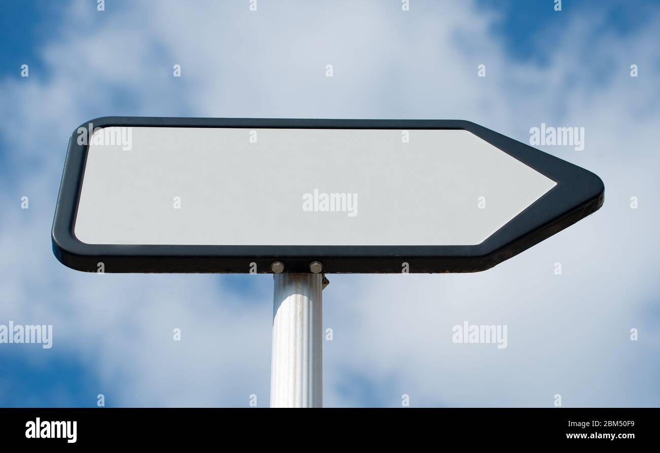 Vista ad angolo basso di un bianco, bianco, che punta il senso, posto di segnale di informazioni contro un cielo blu con le nuvole. Foto Stock