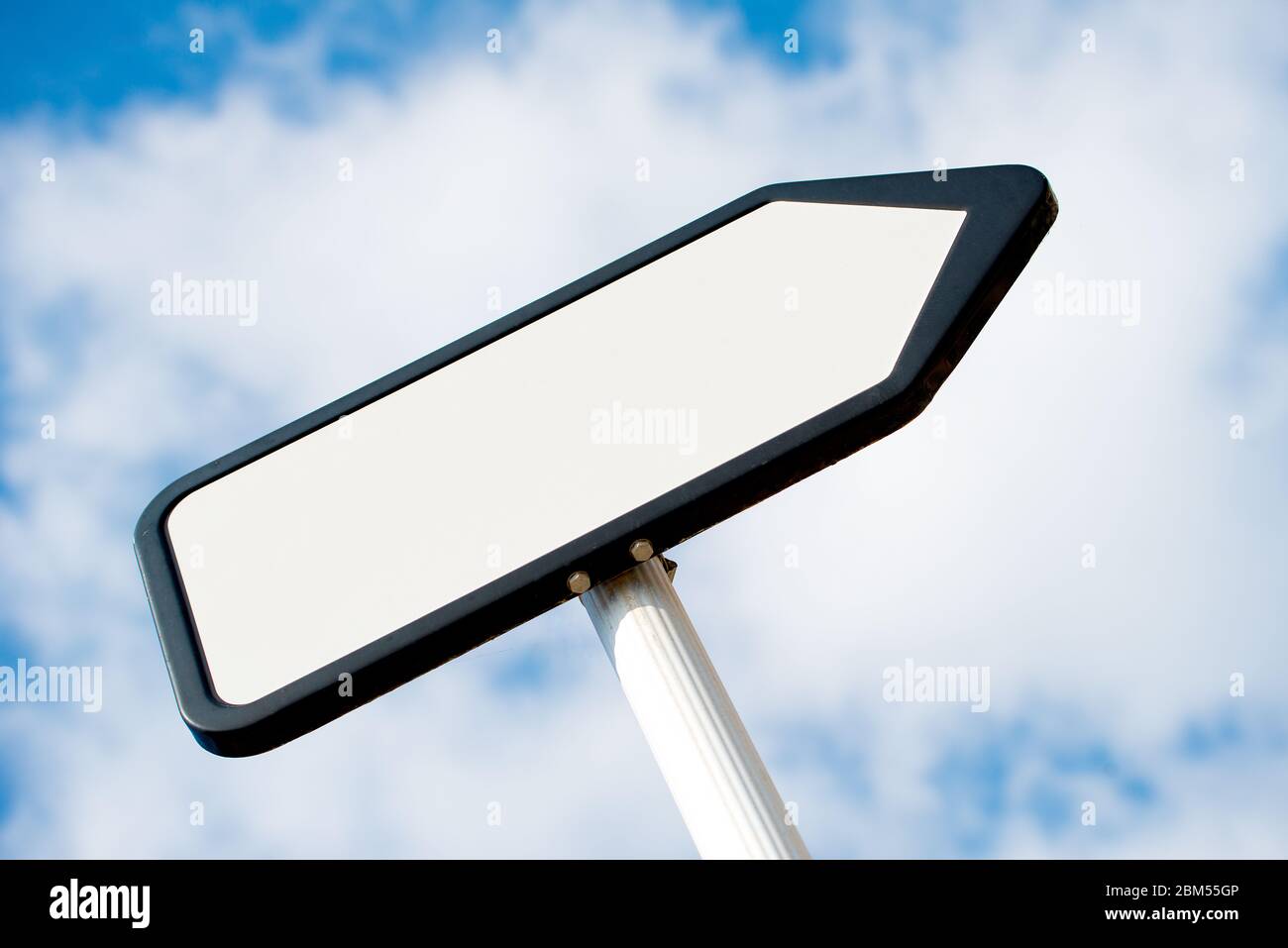 Vista ad angolo basso di un bianco, bianco, che punta il senso, posto di segnale di informazioni contro un cielo blu con le nuvole. Foto Stock