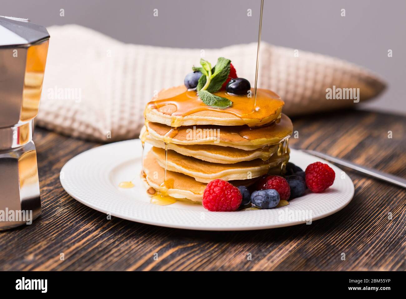 Sciroppo d'acero che versa su una pila di mini pancake. Foto Stock