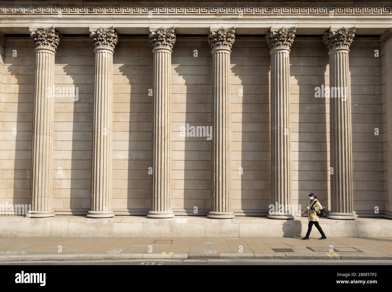 Una donna che indossa una maschera protettiva passa davanti alla Bank of England, Londra, mentre il Regno Unito continua a bloccarsi per contribuire a frenare la diffusione del coronavirus. Foto Stock