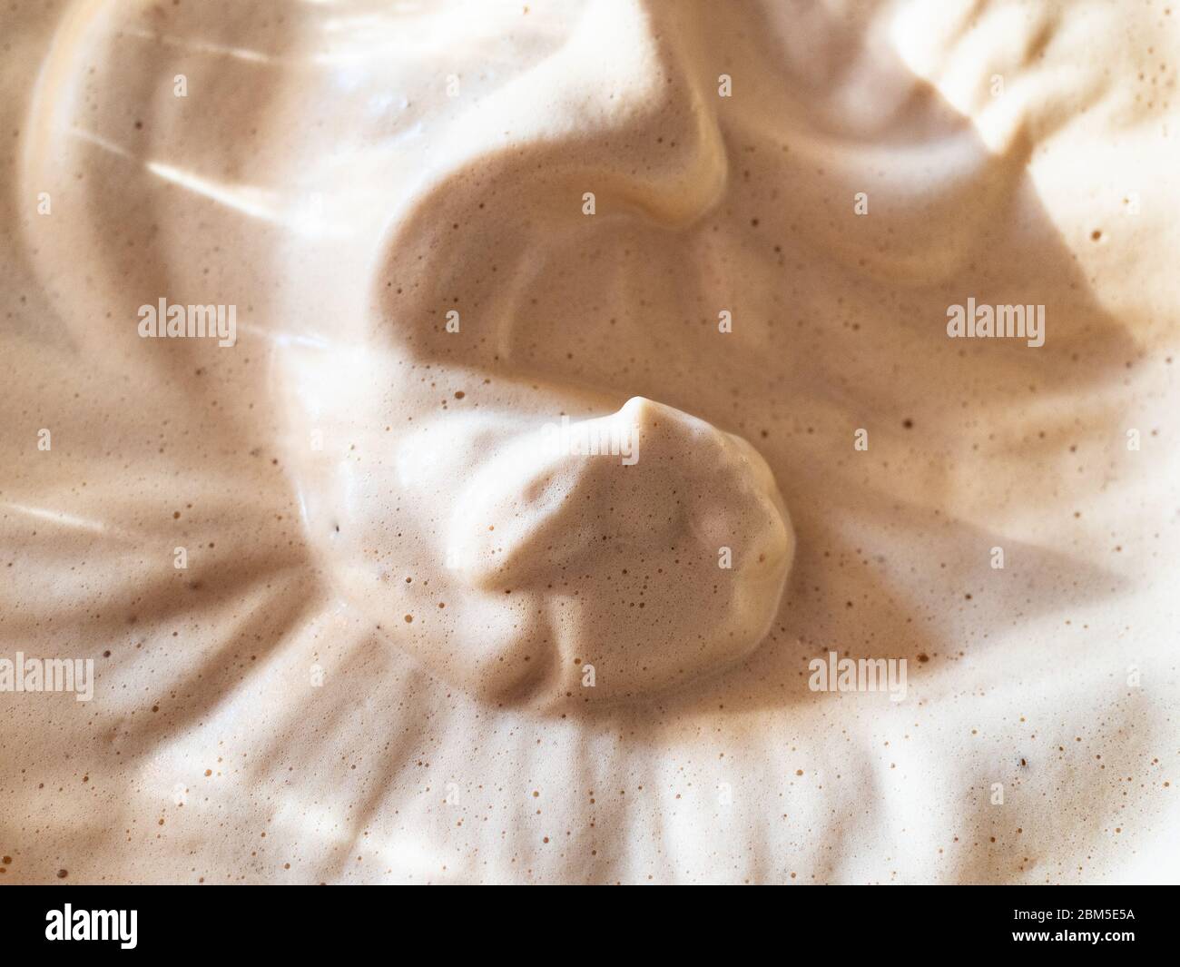 Superficie del caffè Dalgona appena montato (bevanda coreana preparata con la polvere di caffè istantanea, zucchero e acqua calda) primo piano Foto Stock