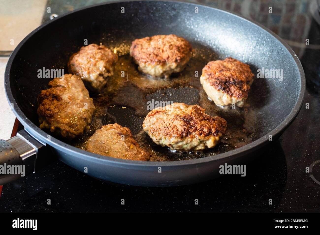 Frittura di Kotleta russa (bistecche di manzo tritate impanate con farina)  in padella su stufa in ceramica in cucina Foto stock - Alamy