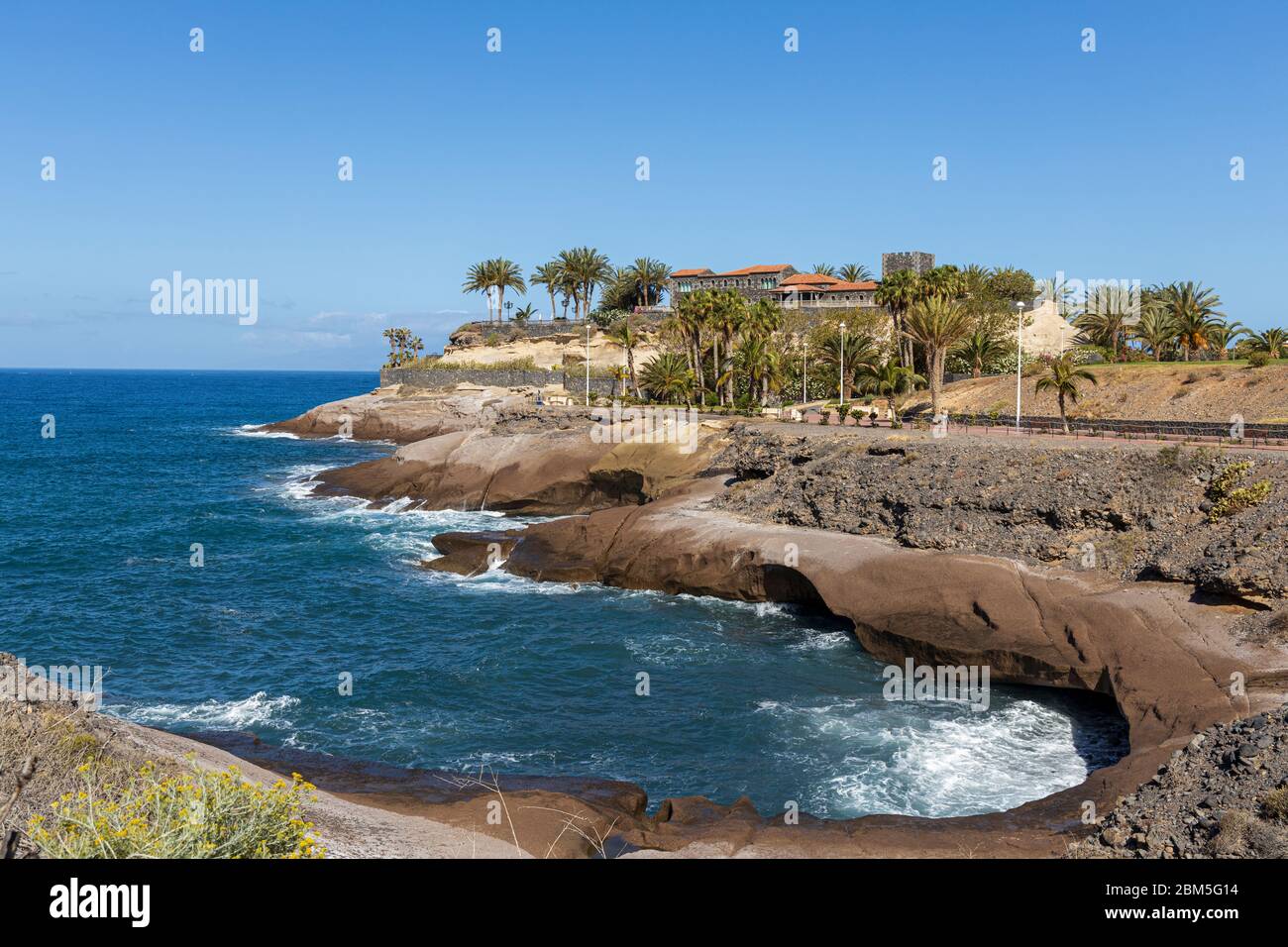 Piccola baia lungo la costa con passaggio pedonale vuoto e il Castillo del Duque durante il Covid 19 Stato di emergenza a Costa Adeje, Tenerife, Isole Canarie Foto Stock