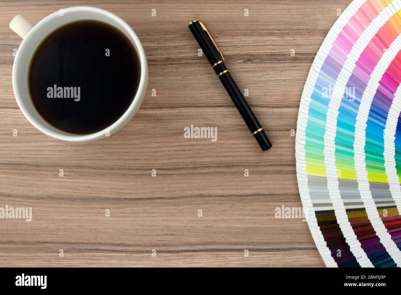 Gamma di carte colore su scrivania in legno con caffè e penna Foto Stock