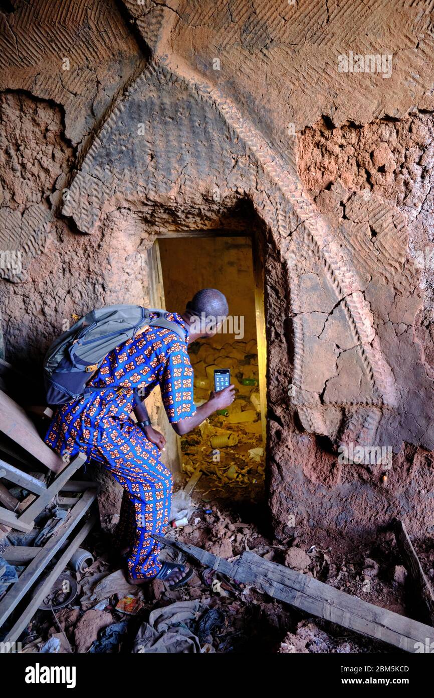 Uomo che indaga sulle rovine di una vecchia casa tradizionale. Foto Stock